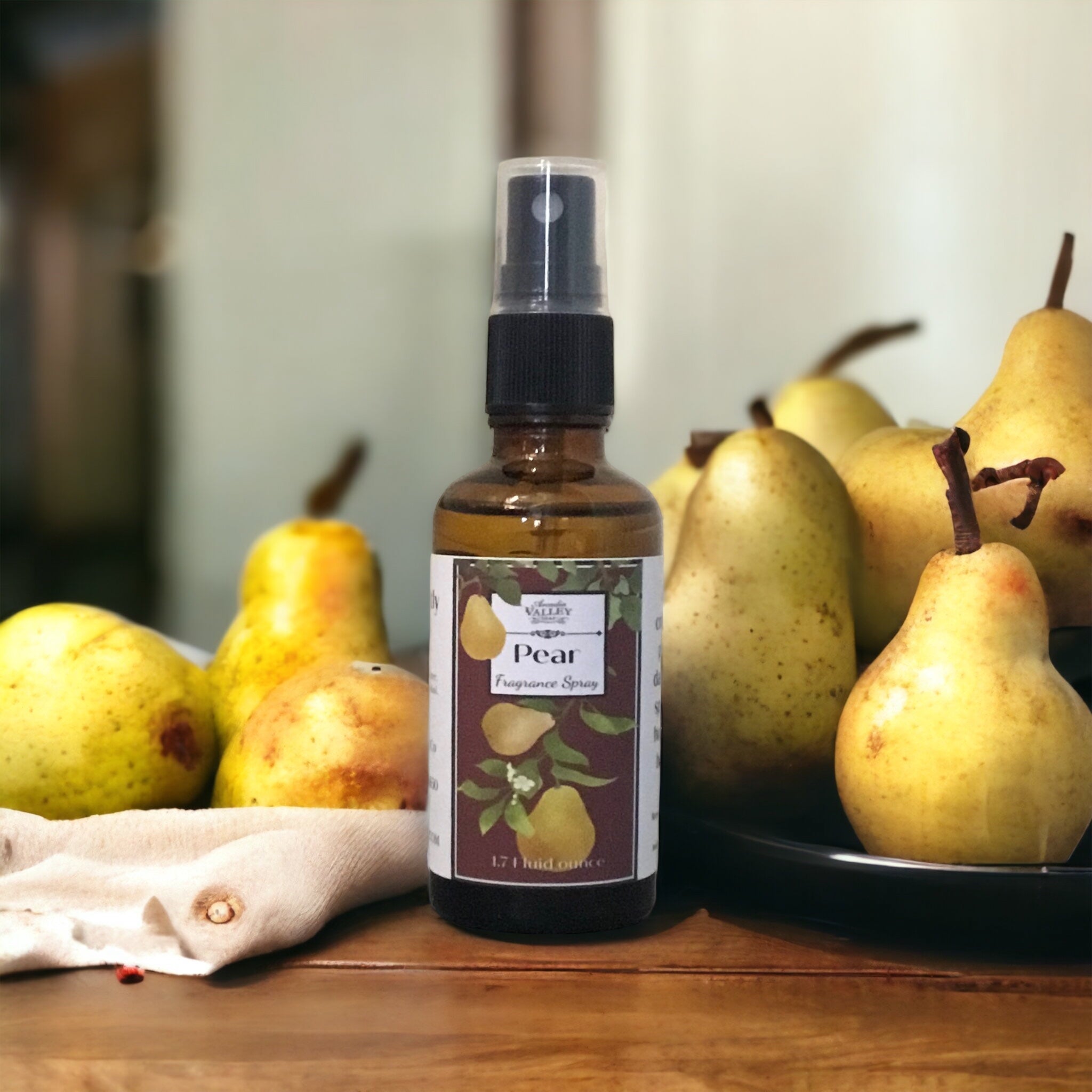 Amber glass bottle with black mist sprayer of Pear fragrance spray sitting on a wooden table with pears on display