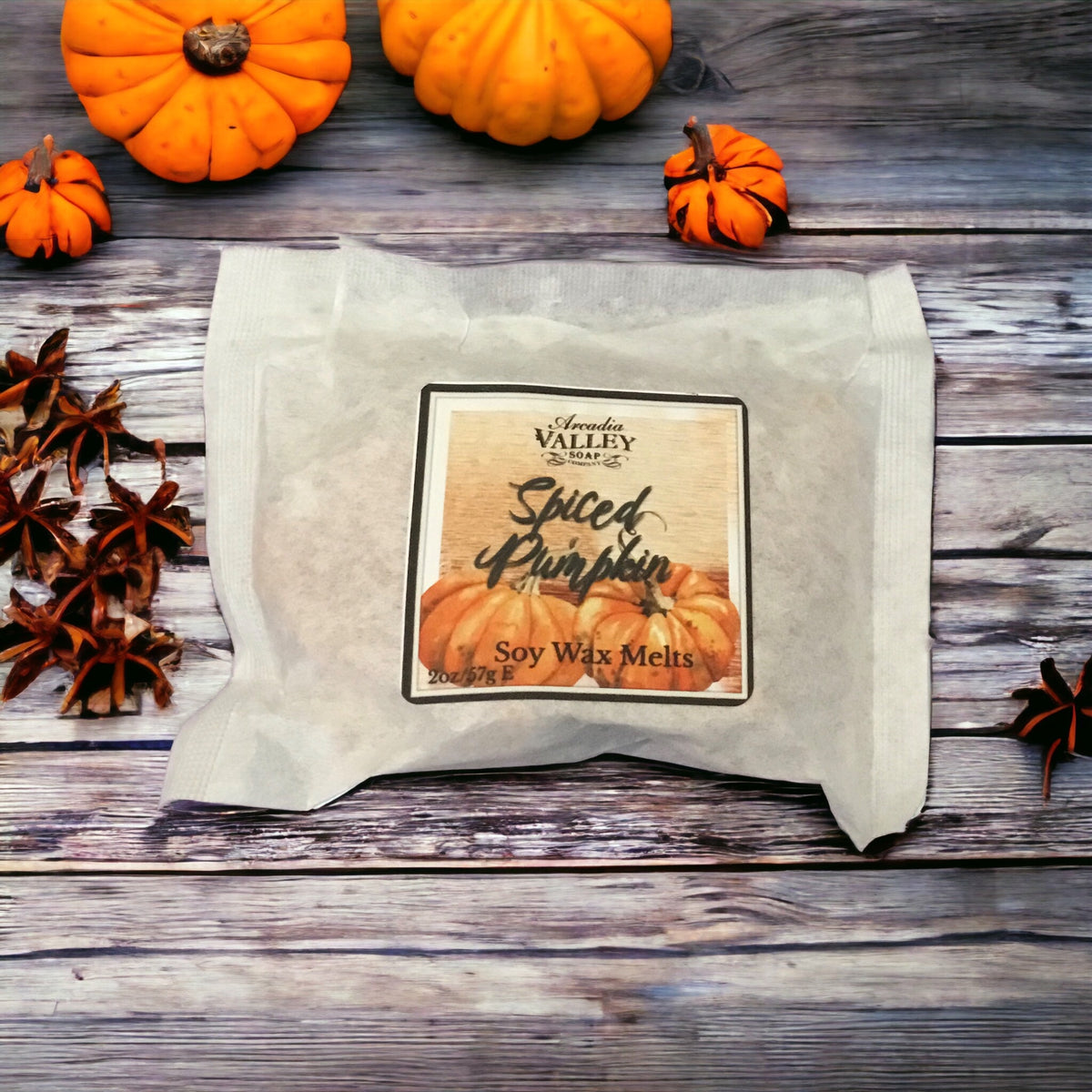 Packed spiced pumpkin fragrance bark melts in a white, light-weight paper pouch with decorative label on a wooden table with pumpkin and spiced on display