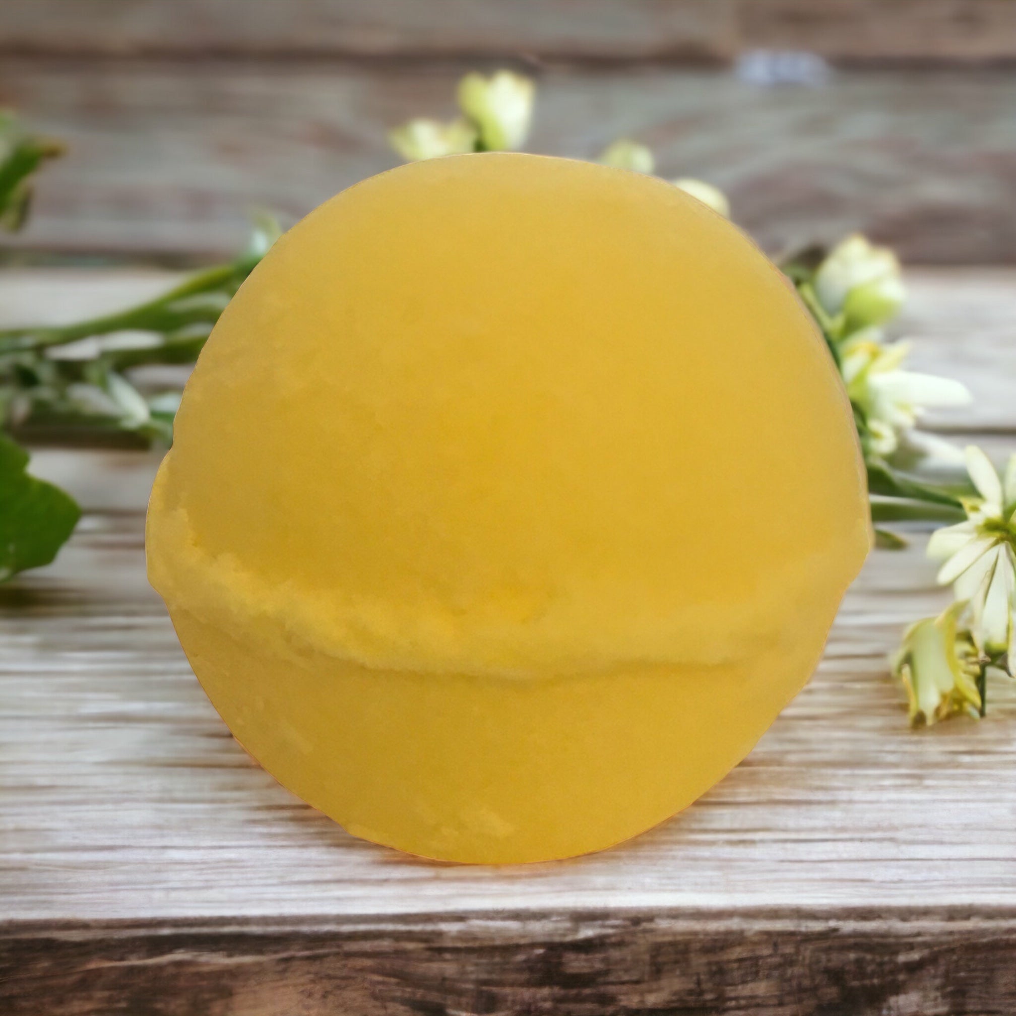 Yellow honeysuckle bath bomb on wooden table with flowers