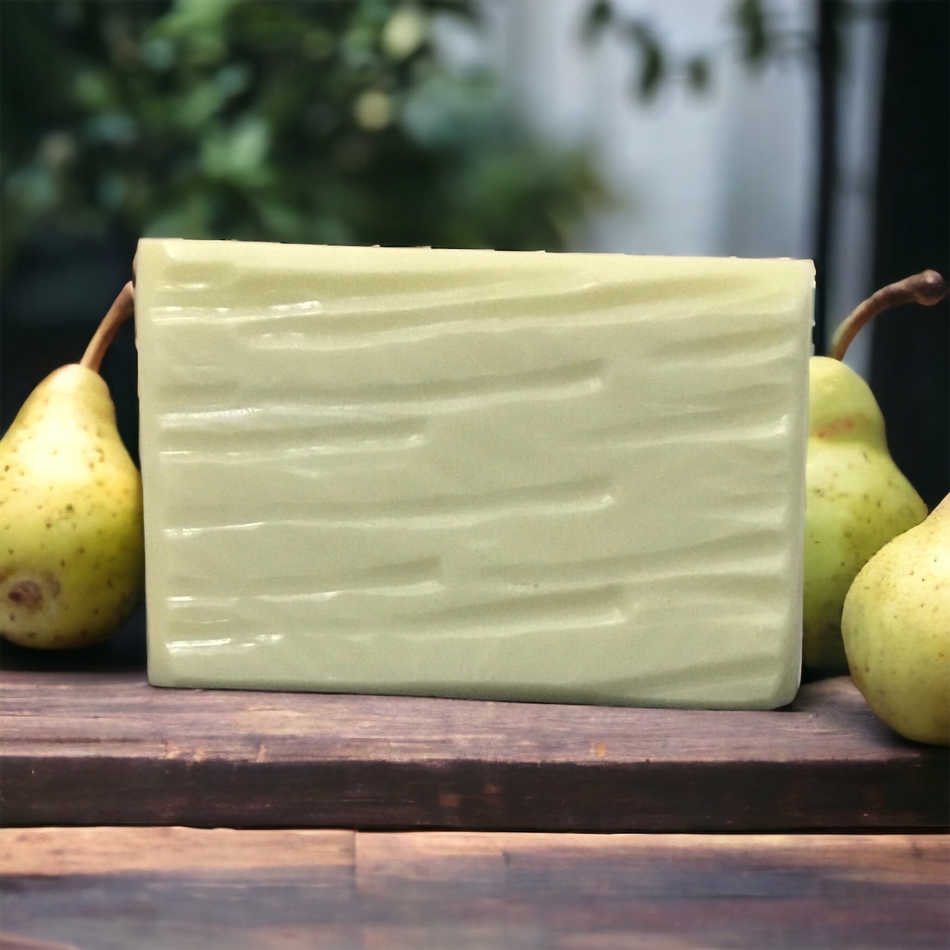 Pale green pear soap on wooden table with pears for display