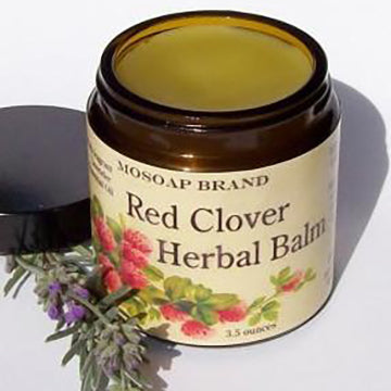 Red Clover Herbal Balm in an amber glass jar with black plastic  screw top